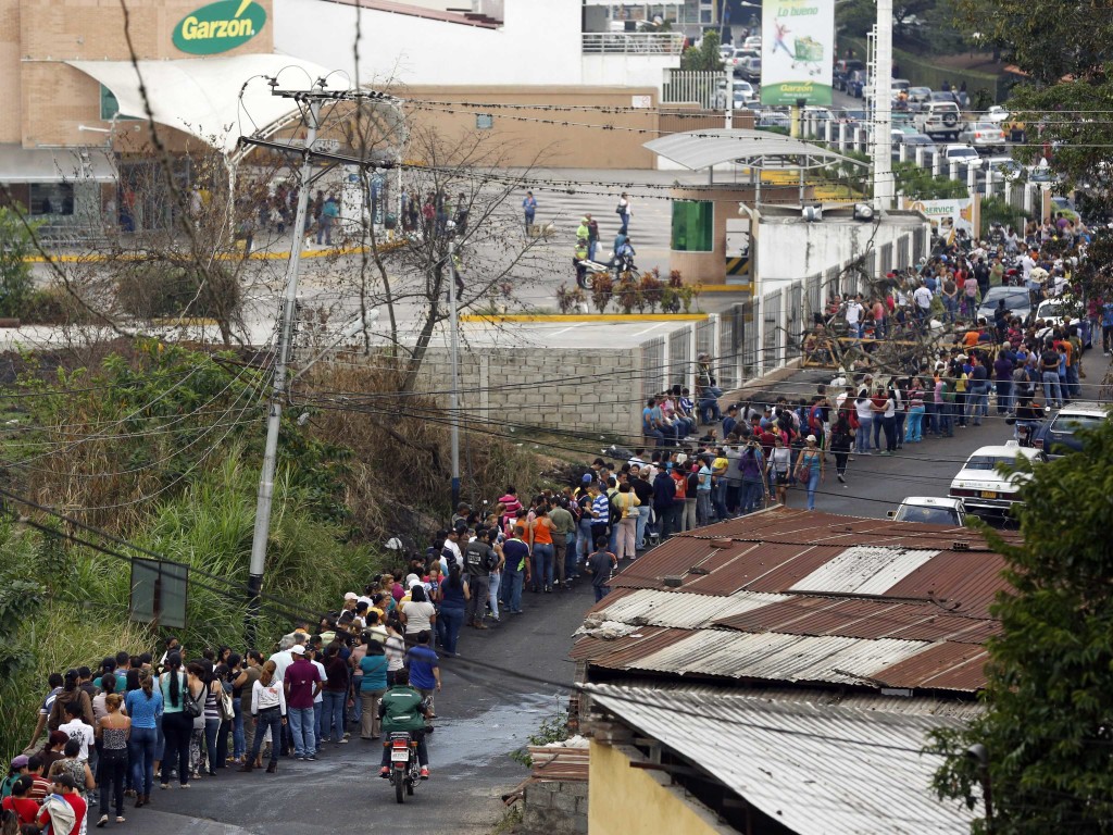 Venezuelans wait in line for food at a supermarket businessinsider.com